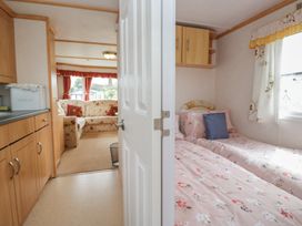 A bedroom with two beds and a door leading to a living area at Holly in Denny