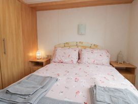 A bedroom with a bed and bedside tables at Holly in Denny