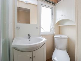 A bathroom with a sink, toilet, and window at Holly in Denny