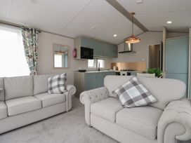 A living room with sofas and an open kitchen at Yew in Denny