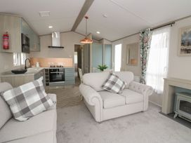 A living room with a couch and kitchenette at Yew in Denny