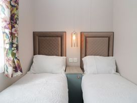 A bedroom with two single beds and a bedside table at Yew in Denny
