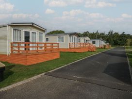 Mobile homes with wooden decks along a paved road at Yew in Denny