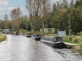 A canal with narrowboats and trees at Yew in Denny