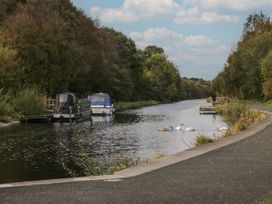 A canal with swans and boats beside a pathway at Yew in Denny