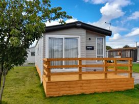 A caravan with a wooden deck located at Yew in Denny