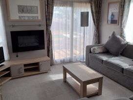 A living room with a coffee table and television at Yew in Denny