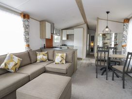 A living room with a sofa and kitchen area at Ash in Denny