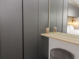 A bedroom with a wardrobe and a mirror at Ash in Denny