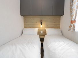 A bedroom with two beds and a bedside lamp at Ash in Denny