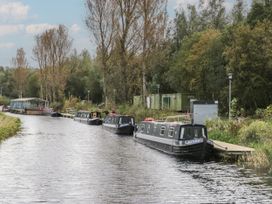 Narrowboats moored along a canal with trees and buildings in the background at Willow in Denny
