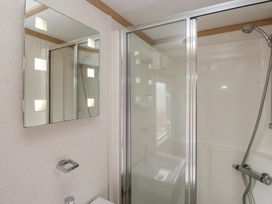 A bathroom with a shower and mirror at Willow in Denny