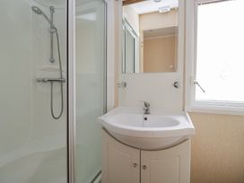 A bathroom with a shower, sink, and mirror at Birch in Denny