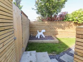 A small garden area with wooden fencing grass stone steps and a white sculpture at Trearddur House Cottage in Trearddur Bay