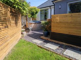 A small garden area with a wooden hot tub stone pavers grass and wooden fences at Trearddur House Cottage in Trearddur Bay