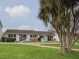 A bungalow with patios and outdoor furniture on a lawn with a large tree in front at Forbes C1 in Yarmouth