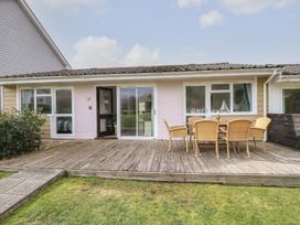 A wooden deck with a table and six chairs outside a single story house at Forbes C1 in Yarmouth