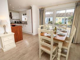 A dining area with a wooden table set for six and a kitchen with white cabinets at Forbes C1 in Yarmouth