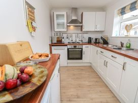 A kitchen with white cabinets wooden countertops a stove microwave and fruit on the counter at Forbes C1 in Yarmouth