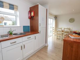 A kitchen with white cabinets and a wood countertop next to a dining area with a table and chairs at Forbes C1 in Yarmouth