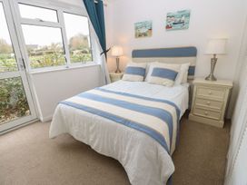 A bedroom with a bed with blue and white striped bedding two bedside tables with lamps and a window with blue curtains at Forbes C1 in Yarmouth