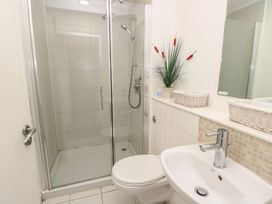 A bathroom with a shower, toilet, sink, mirror, and decorative plant at Forbes C1 in Yarmouth