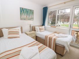 A bedroom with two single beds a nightstand with a lamp and a window showing an outdoor area at Forbes C1 in Yarmouth