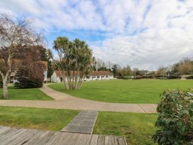 A large grassy area with a paved pathway and trees near single-story buildings at Forbes C1 in Yarmouth