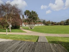 A lawn with trees and a pathway leading to a row of single-story buildings at Forbes C1 in Yarmouth