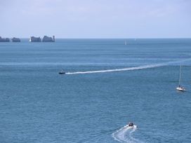 A sea view with boats and a lighthouse near rock formations at Forbes C1 in Yarmouth