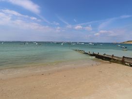 A sandy beach with a wooden pier and boats on the water at Forbes C1 in Yarmouth