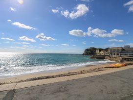 A beachfront with kayaks on the sand and buildings near cliffs at Forbes C1 in Yarmouth