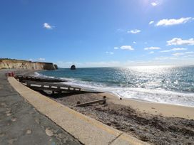 A beach with a seawall and wooden ramps near cliffs under a blue sky at Forbes C1 in Yarmouth