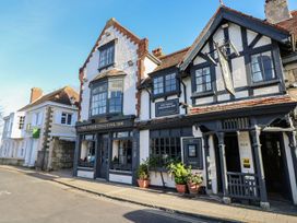 A street view of the Bugle Coaching Inn with white and black timber framed buildings and potted plants outside at Forbes C1 in Yarmouth