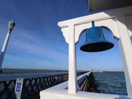 A blue bell hanging on a white structure near a wooden pier over water at Forbes C1 in Yarmouth