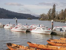 Boats moored at a dock with trees and mountains in the background at Claife Flights Bowness-On-Windermere