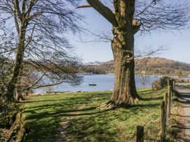 A lakeside view with a tree and a boat at Claife Flights in Bowness-On-Windermere