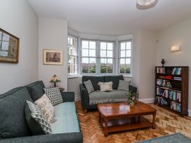 A living room with two green sofas a wooden coffee table a bookshelf and a bay window at Middle Lodge near Taunton