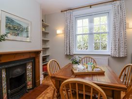A dining room with a wooden table and chairs a tray with teapot and cups a window with curtains and a fireplace at Middle Lodge near Taunton