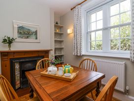 A dining area with a wooden table and chairs a tray with a teapot and cups a fireplace and a window with curtains at Middle Lodge near Taunton