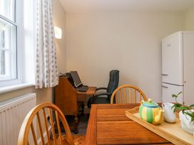 A small dining area with wooden table and chairs a computer desk and chair near a window and a white refrigerator at Middle Lodge near Taunton