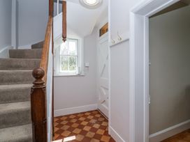 A hallway with carpeted stairs wooden banister a window and a white door at Middle Lodge near Taunton