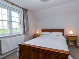 A bedroom with a wooden bed and two wooden bedside tables with lamps near a window at Middle Lodge near Taunton