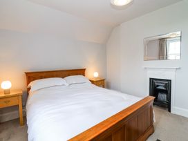 A bedroom with a wooden bed a white duvet two bedside tables with lamps a fireplace and a mirror at Middle Lodge near Taunton