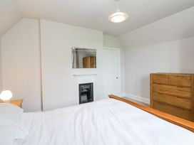 A bedroom with a wooden bed frame a white bedspread a wooden dresser a small fireplace and a mirror on the wall at Middle Lodge near Taunton