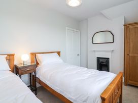 A bedroom with two single beds a wooden nightstand with a lamp a white door a fireplace with a mirror above and a wooden wardrobe at Middle Lodge near Taunton
