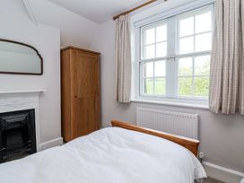 A bedroom with a wooden wardrobe bed white bedding a window with curtains and a fireplace at Middle Lodge near Taunton