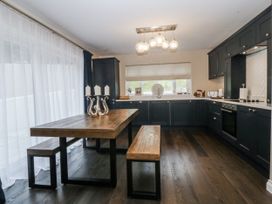 A kitchen with a wooden table and benches at Tyn Y Coed