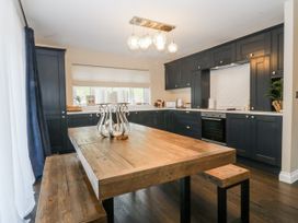 A kitchen with a wooden table and dark cabinets at Tyn Y Coed