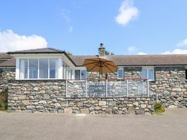 An outdoor area with a stone house and a table under an umbrella at Ysgubor Newydd Parc Isaf Dyffryn Ardudwy